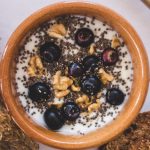 Top view of a nutritious bowl with yoghurt, blueberries, chia seeds, and walnuts.